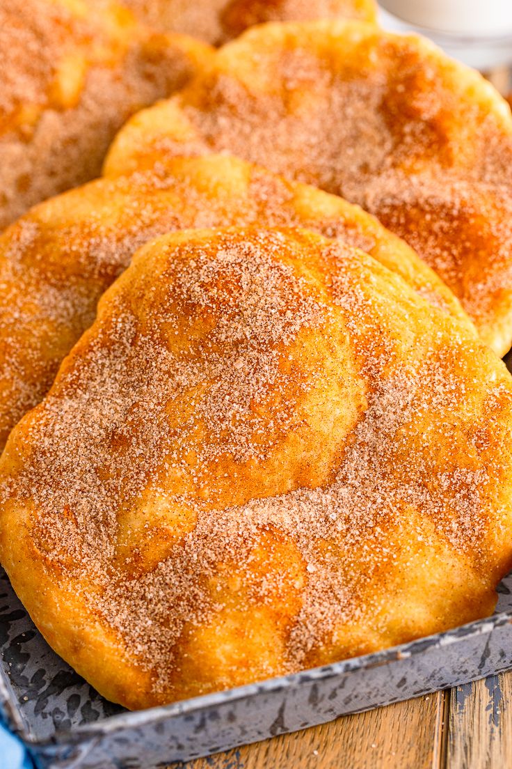 three sugared doughnuts sitting on top of a pan next to a cup of coffee