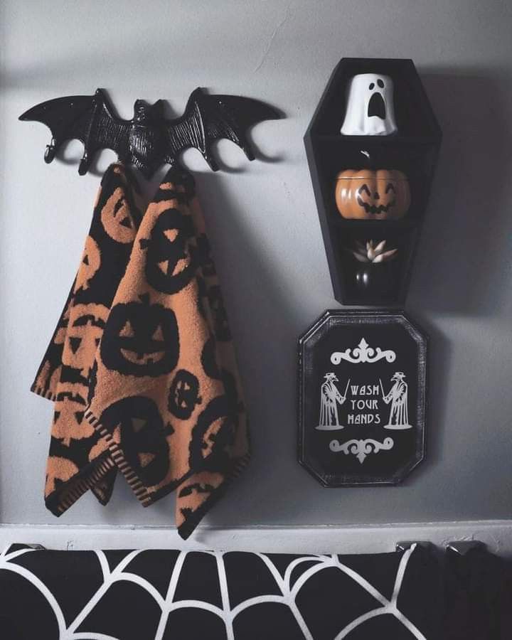 two halloween decorations are hanging on the wall next to a shelf with candles and other items