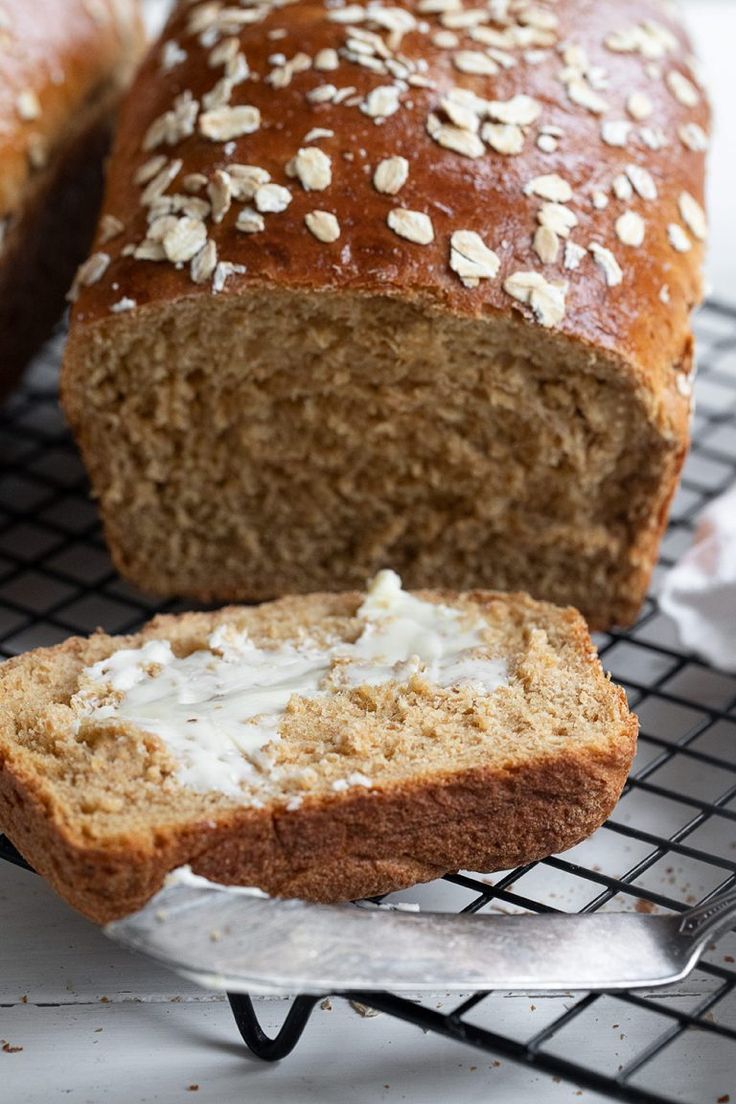 a loaf of bread sitting on top of a cooling rack next to a piece of bread