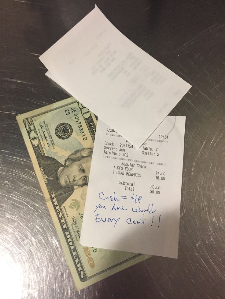 a stack of cash sitting on top of a table next to a note with writing on it