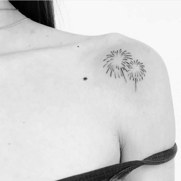 a black and white photo of a woman's shoulder with a tattoo design on it