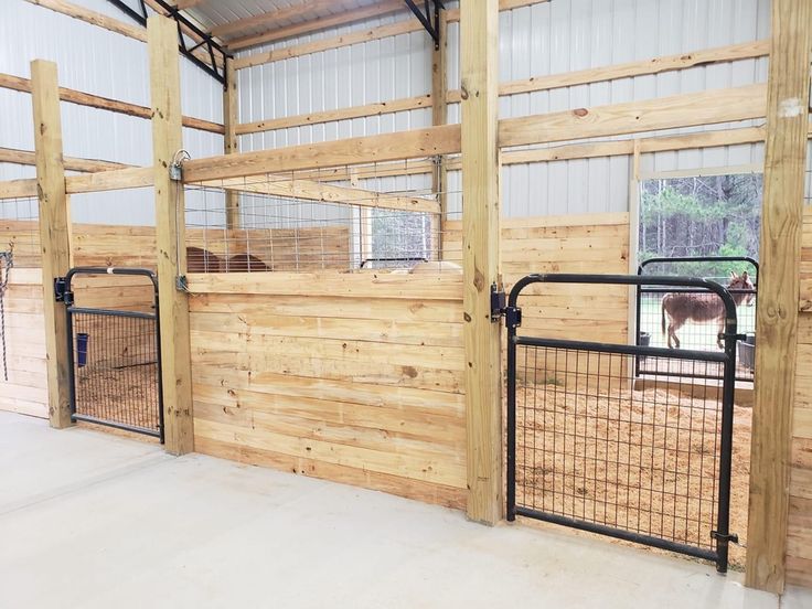 the inside of a barn with wooden walls and metal gated in area for horses