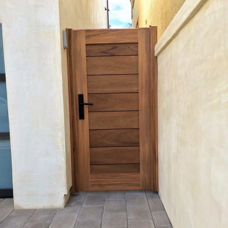 a wooden door on the side of a white wall next to a tiled floor and stairs