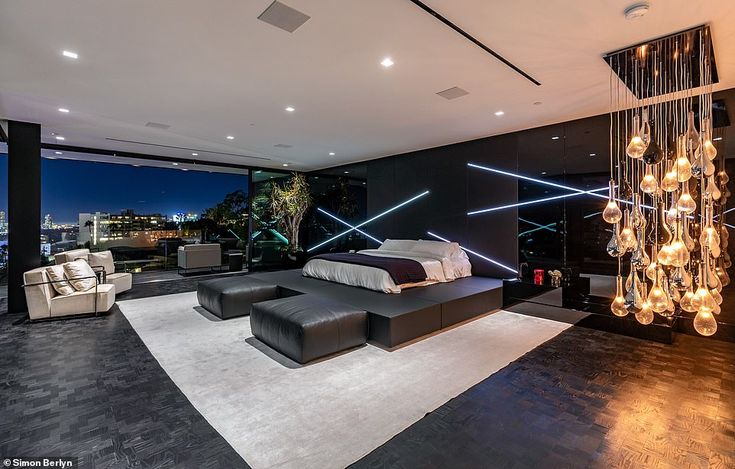 a modern bedroom with black walls and white carpeted flooring, lighted by crystal chandeliers