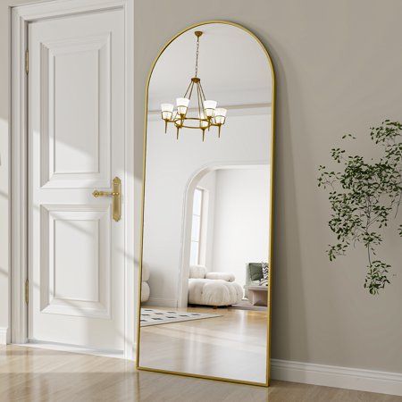 a large mirror sitting on top of a hard wood floor next to a white door