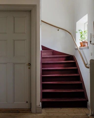 an open door leading up to a set of stairs in a white walled room with wooden floors