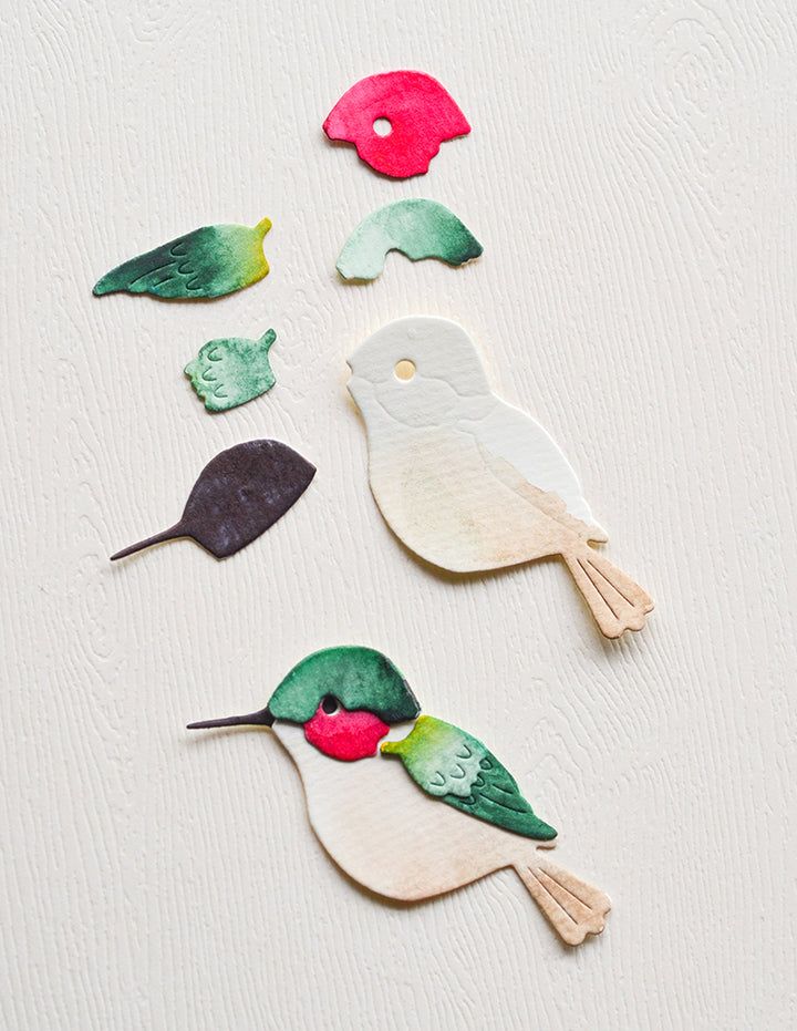 paper cut out birds sitting on top of a white surface with red, green and blue shapes