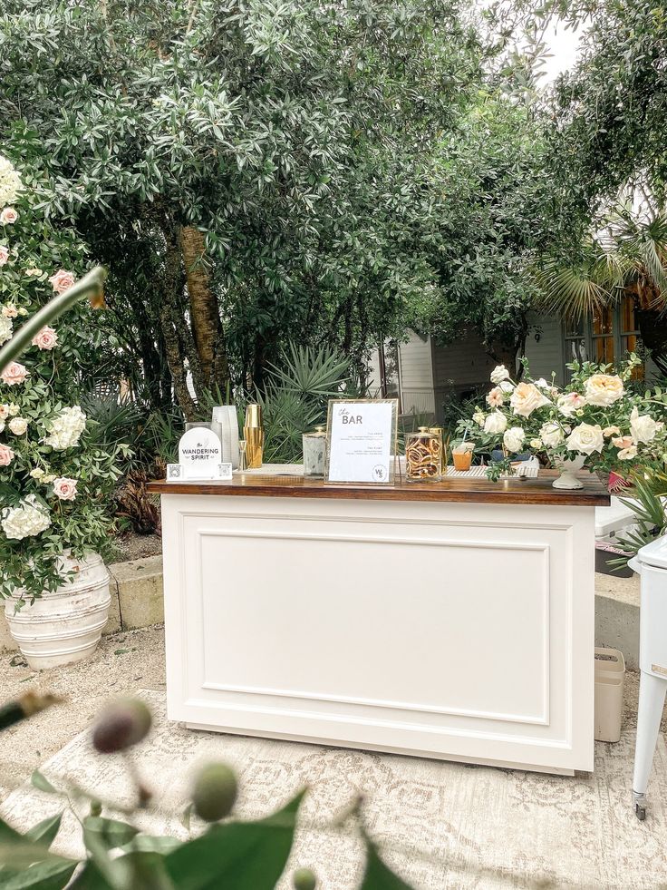 a white reception table with flowers and greenery in the background