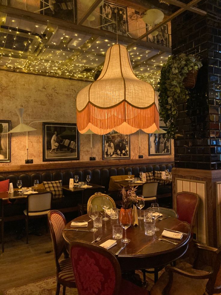 a dining room with tables, chairs and lights hanging from the ceiling over it's head