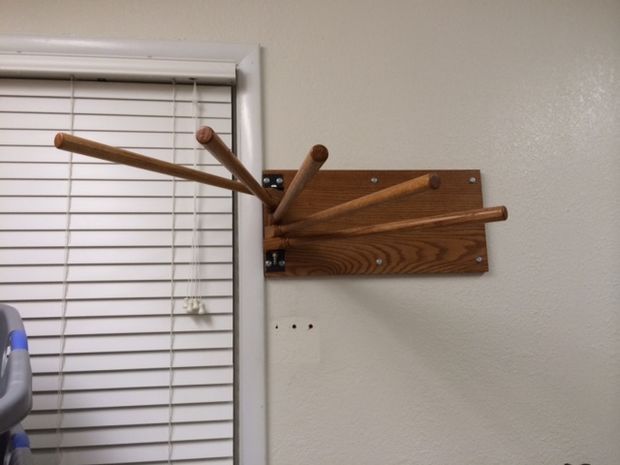 a wooden rack with baseball bats hanging from it's side next to a window