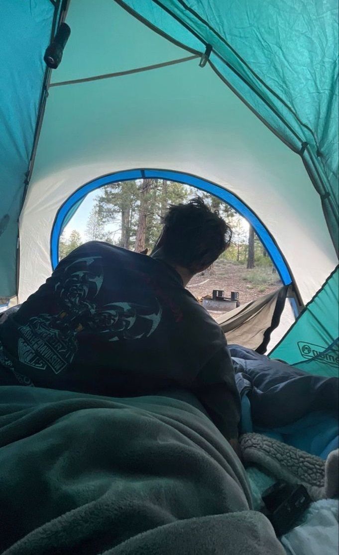 a man sitting inside of a tent next to a forest