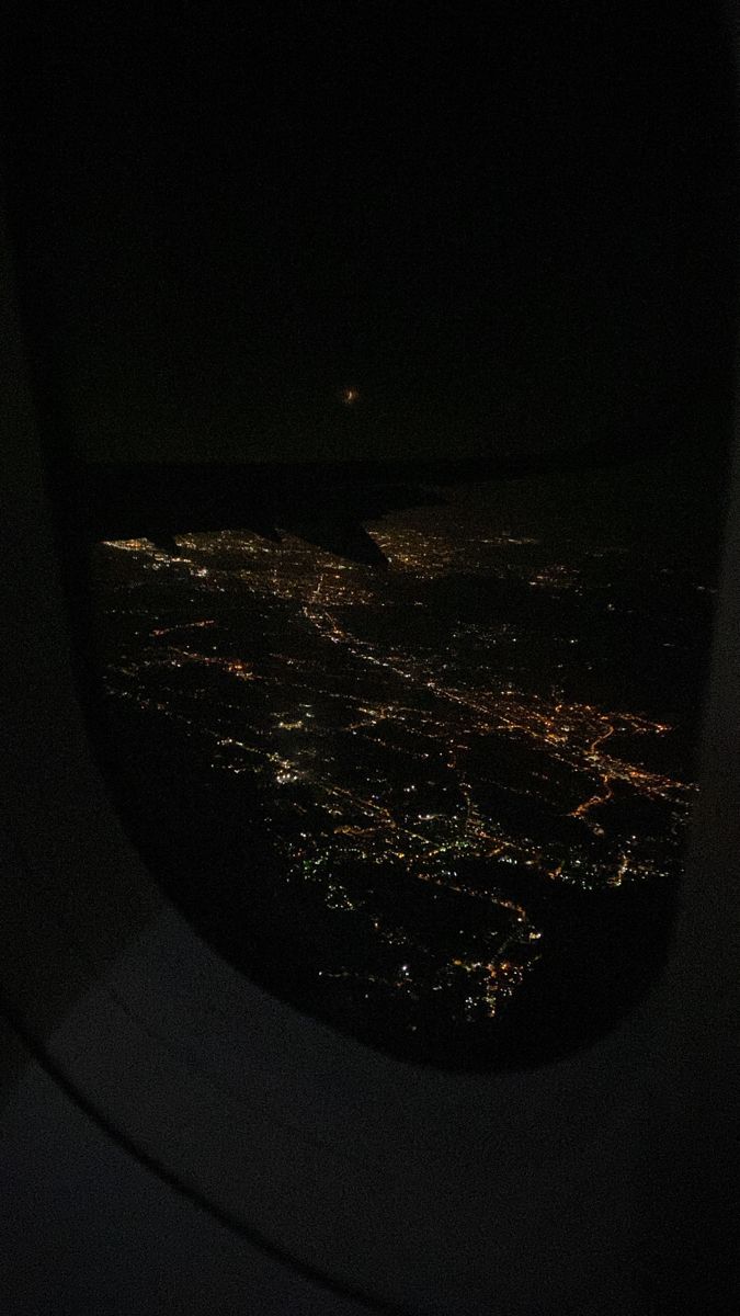 the view out an airplane window at night from inside, with lights in the distance