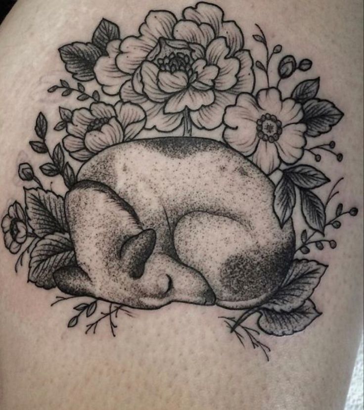 a black and white photo of a skull with flowers on it's back shoulder