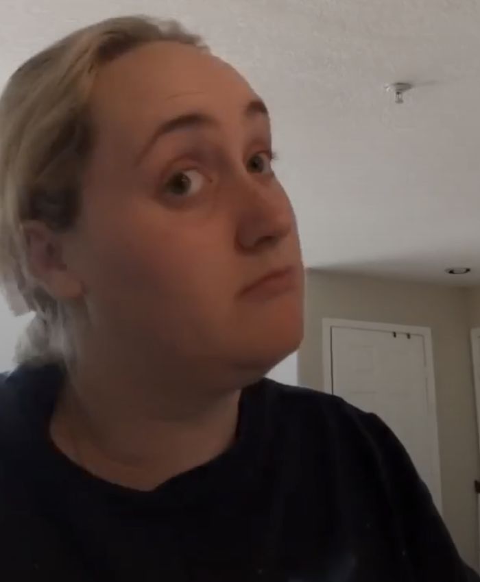 a woman with blonde hair looking up at the ceiling while wearing a black t - shirt