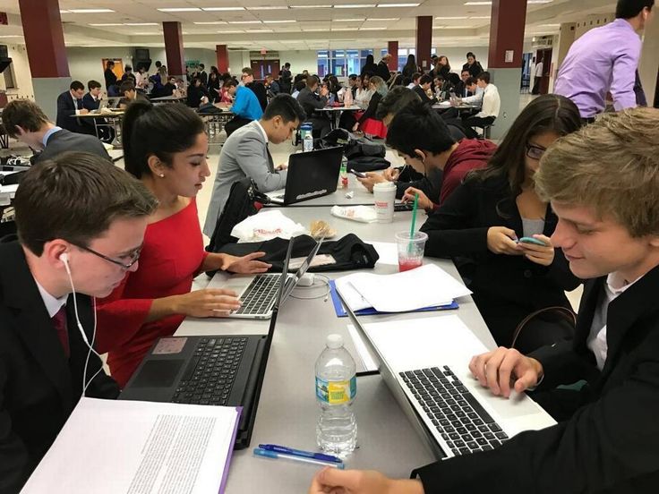 several people sitting at tables with laptops and papers