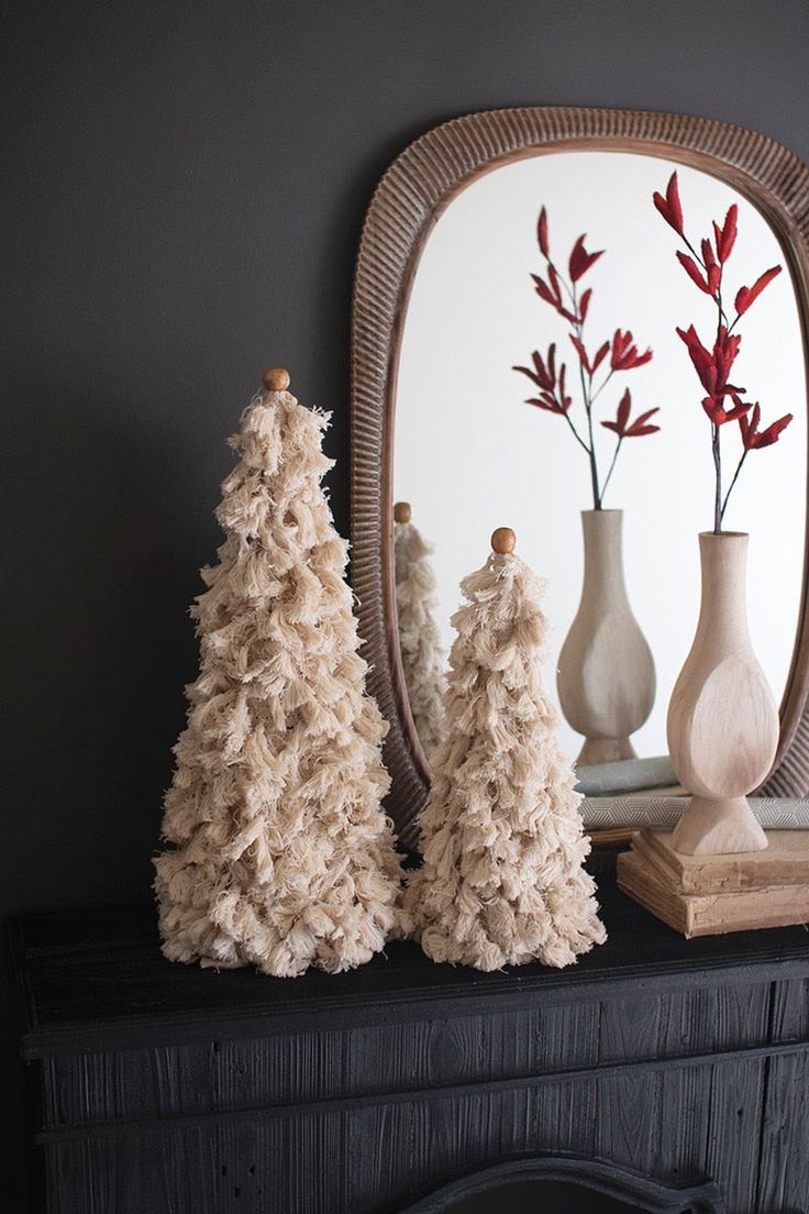 three small trees are on a mantle in front of a mirror