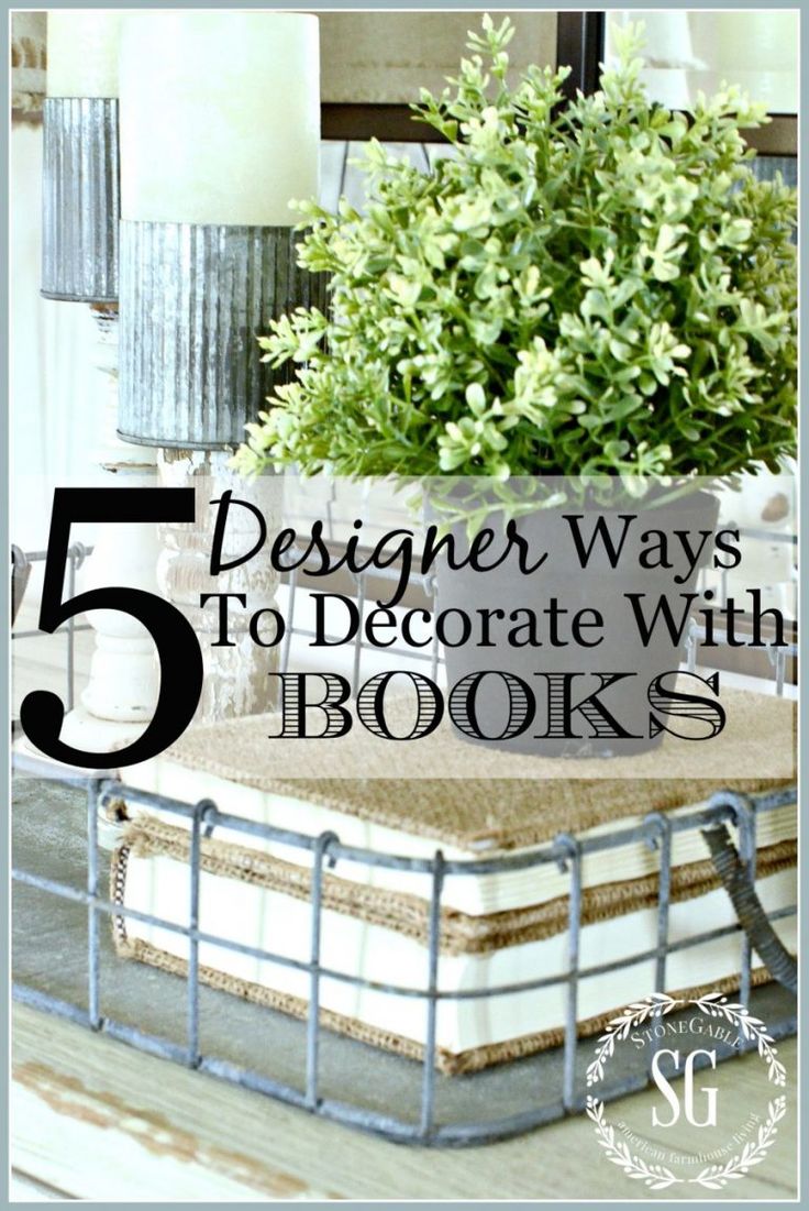 a table topped with books and a vase filled with green plants on top of it