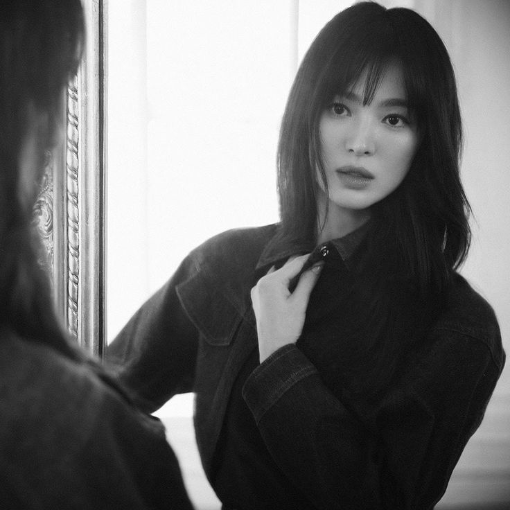 black and white photograph of a woman in front of a mirror with her tie undone