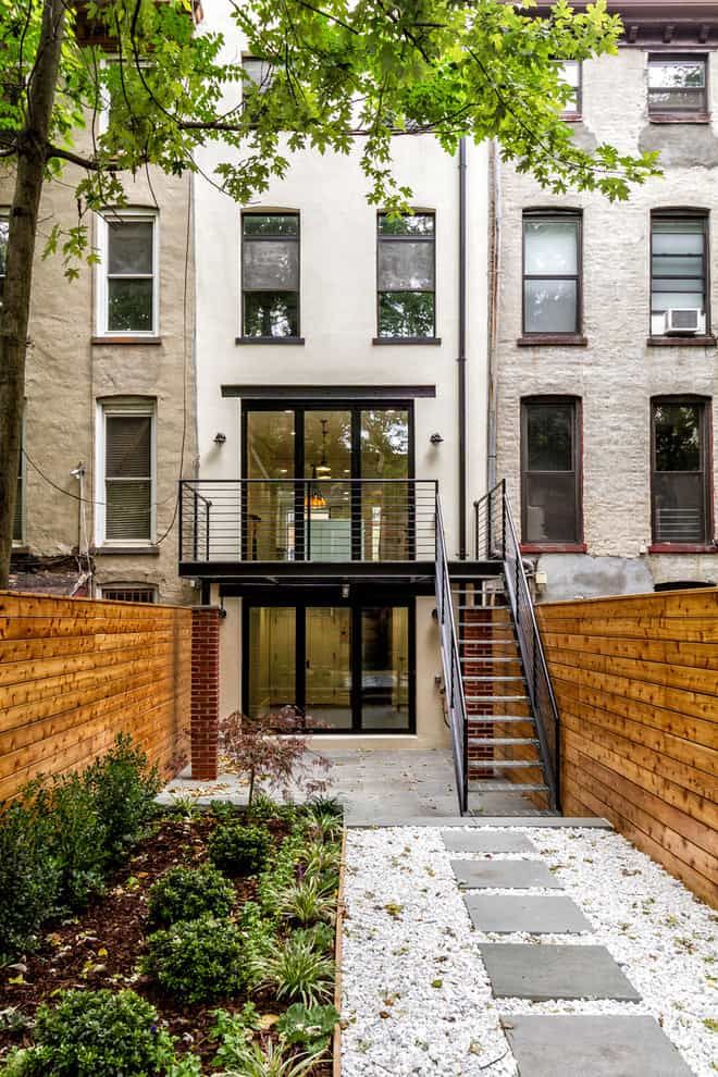 an apartment building with stairs leading up to the front door and side entry area, surrounded by trees