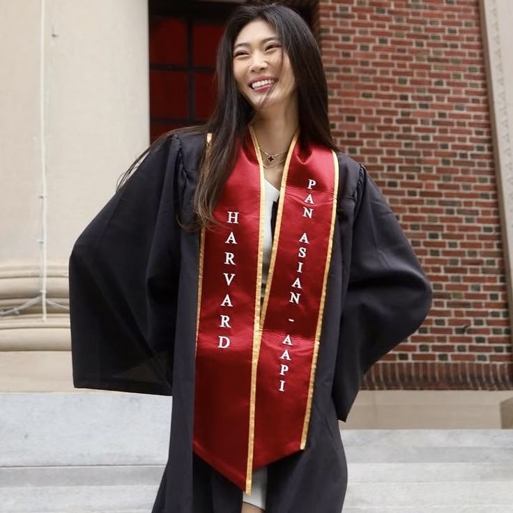 a woman in a graduation gown and cap standing on steps with her arms behind her back