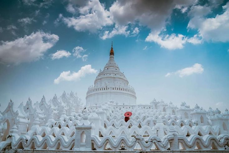 a very tall white building with a red umbrella in the middle of it's roof