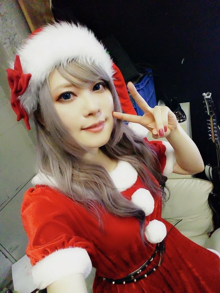 a woman in a red dress and santa hat making the peace sign with her hand