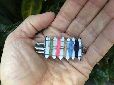 a person holding five different colored pins in their palm, one is white and the other is blue