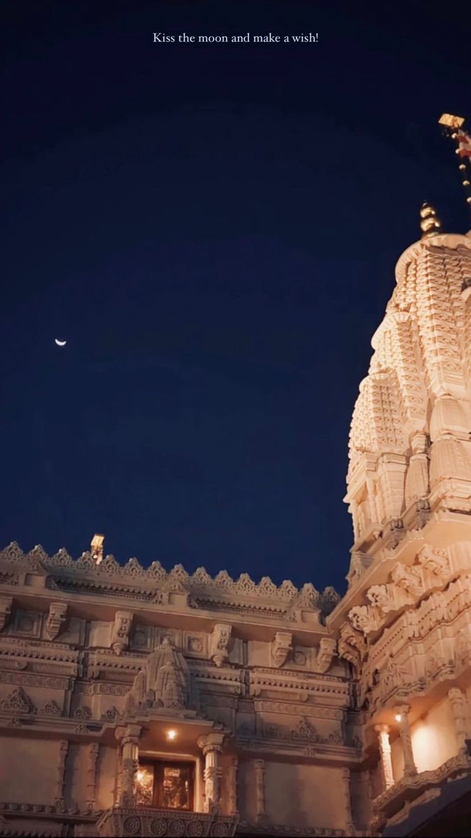 the top of a building with a clock on it's face and moon in the sky