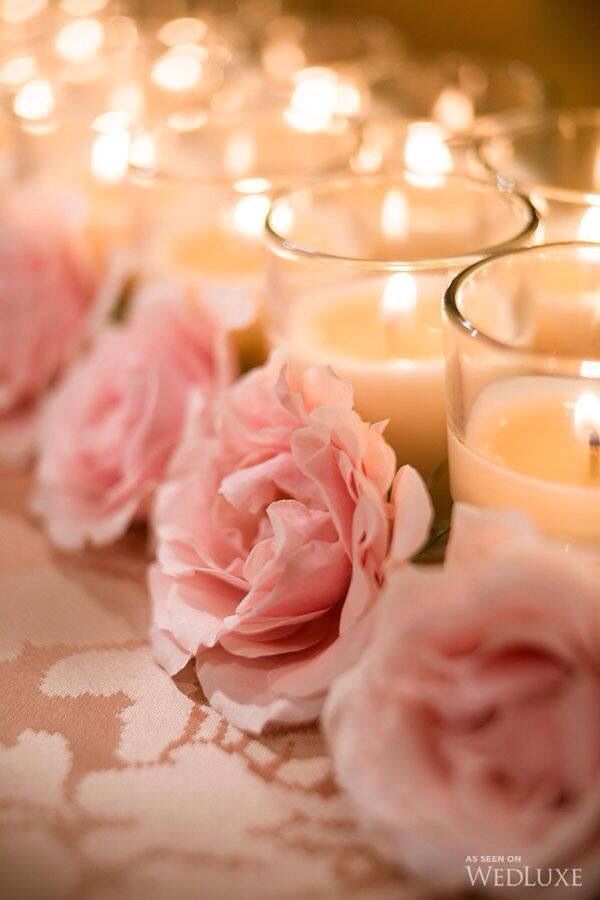 pink roses and candles are lined up on a table