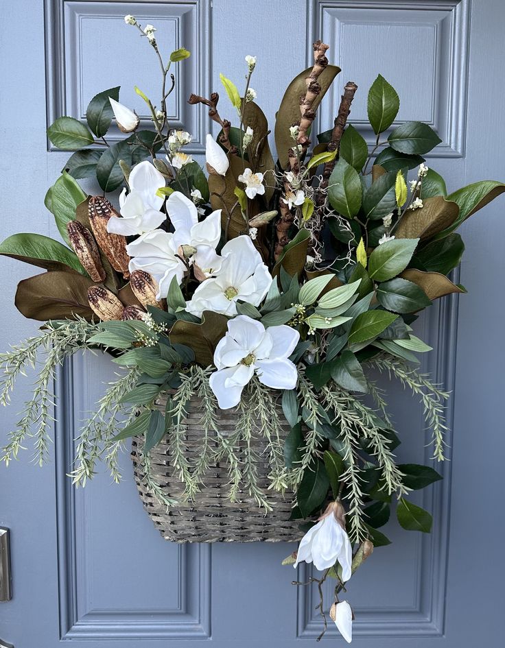 a basket filled with white flowers sitting on top of a door