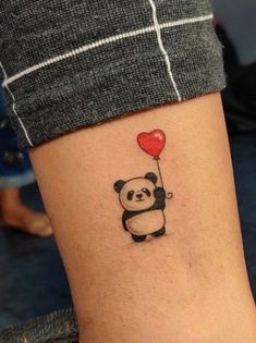 a panda holding a red heart balloon tattoo on the leg, it is black and white