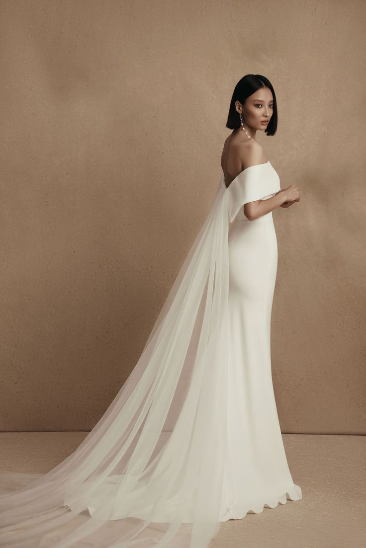 a woman in a white wedding dress with a long veil on her head and shoulder