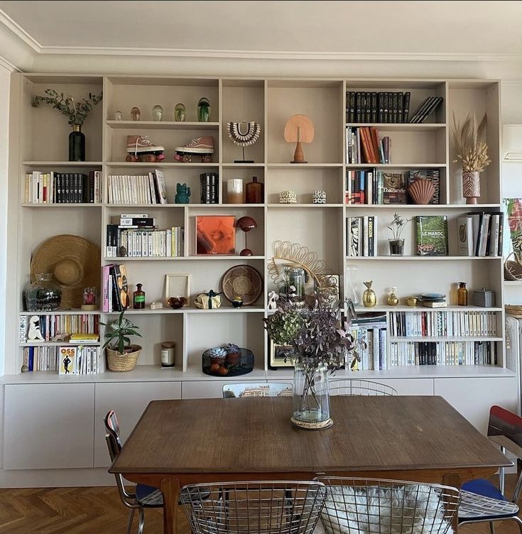 a dining room table with chairs and bookshelves in the wall behind it,