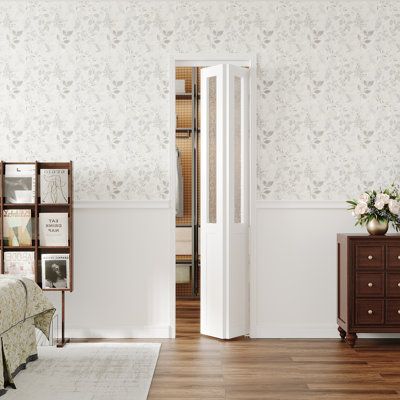 a bedroom with a bed, dresser and mirror next to a wallpapered wall