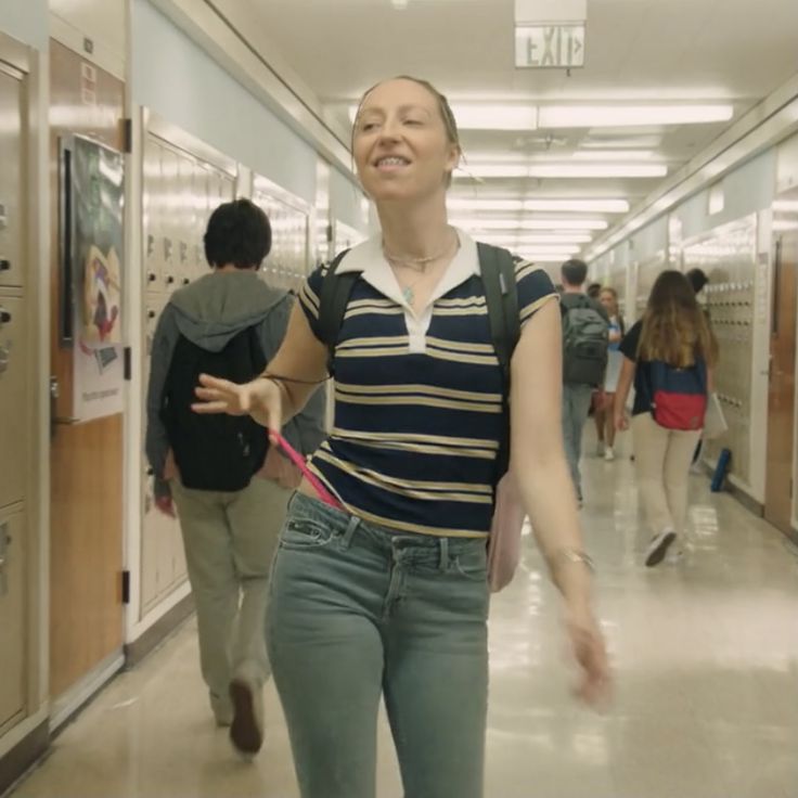 a woman is walking down the hallway with her hand in her pocket and looking up