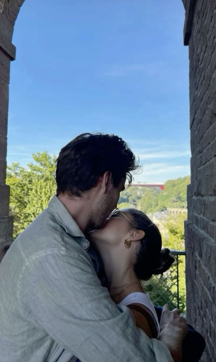 a man and woman kissing in an archway