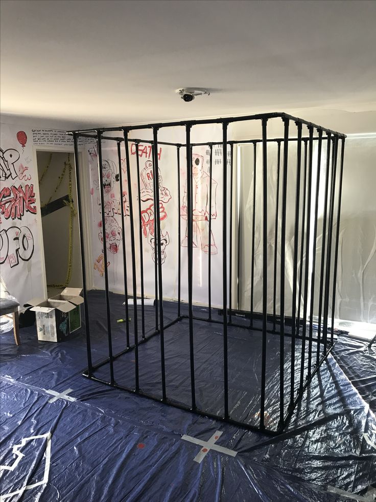 the room is covered in plastic and has graffiti on the walls, including an open gate