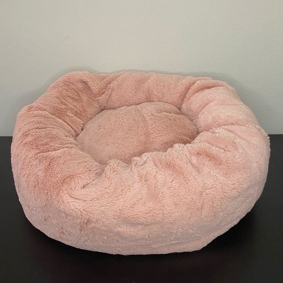 a pink dog bed sitting on top of a black table