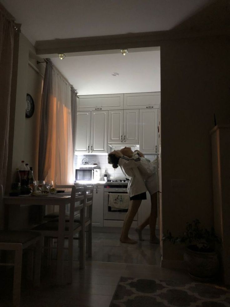 a woman standing in a kitchen next to a stove top oven