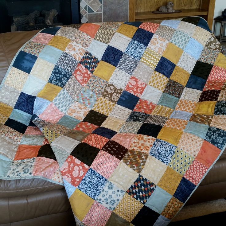 a couch with a quilt on it and a fire place in the backround