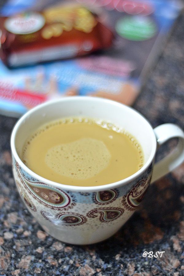 a cup of coffee sitting on top of a counter next to some candy bar wrappers