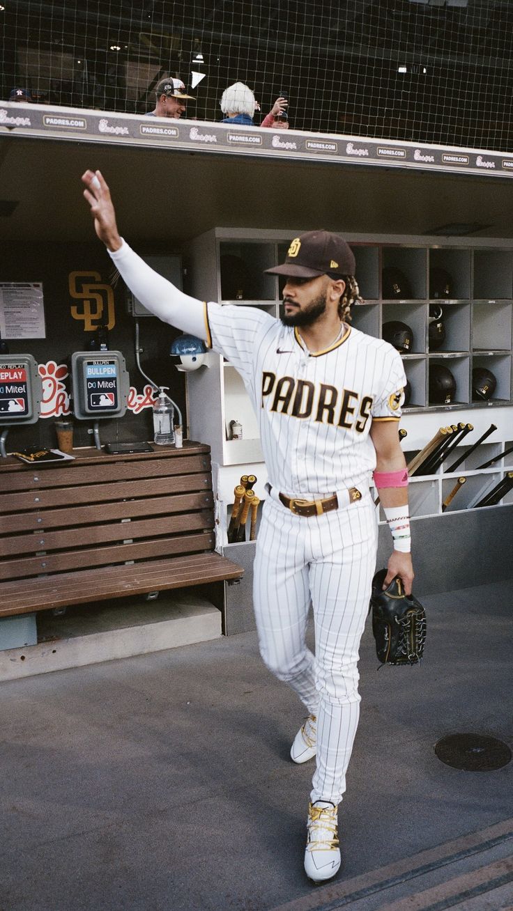 a baseball player walking out of the dugout with his hand in the air,