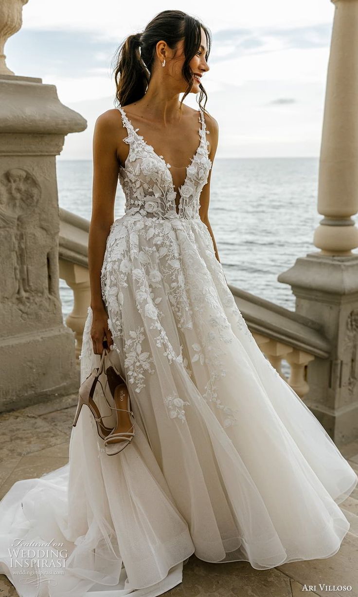 a woman in a wedding dress is standing on the steps by the water with her handbag