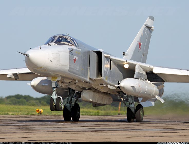 a fighter jet sitting on top of an airport tarmac with grass in the background