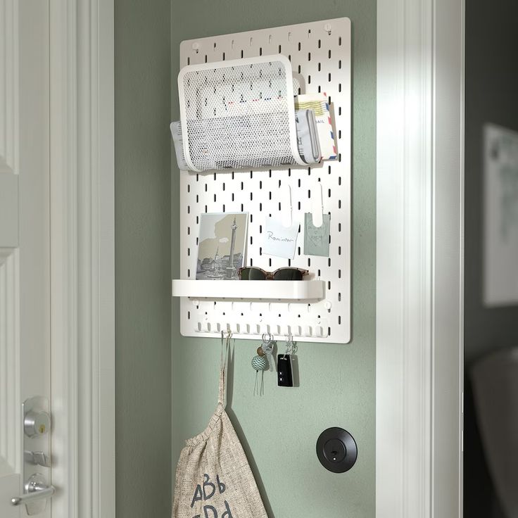 a white wall mounted shelf next to a door with a bag hanging from it's side