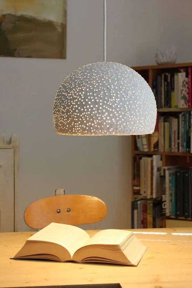 an open book sitting on top of a wooden table next to a lamp and bookshelf