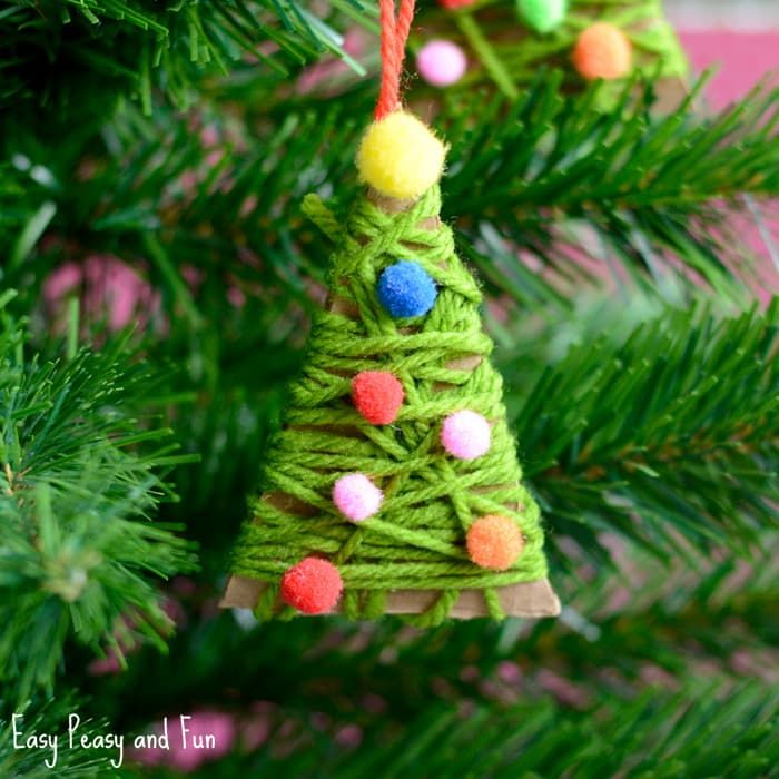 a christmas tree ornament hanging from a pine tree with pom - poms