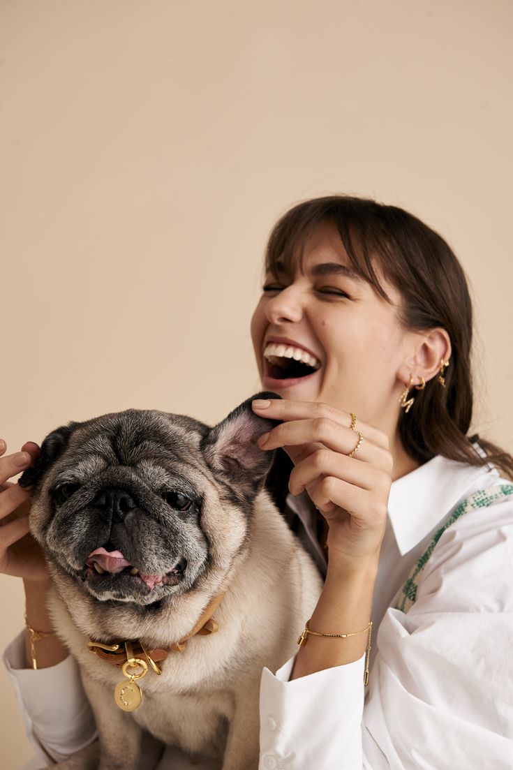 a woman brushing her teeth next to a small pug dog on the lapel