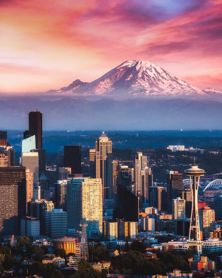 the city is surrounded by tall buildings with a snow capped mountain in the back ground