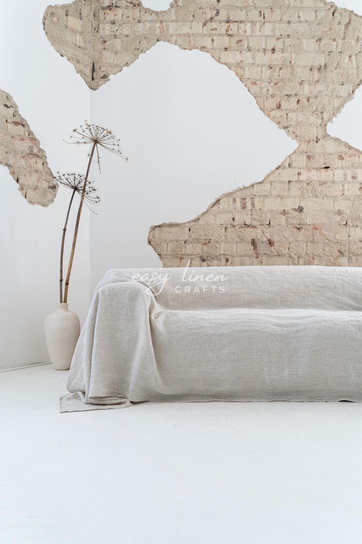 a bed with a white blanket on top of it next to a vase filled with flowers